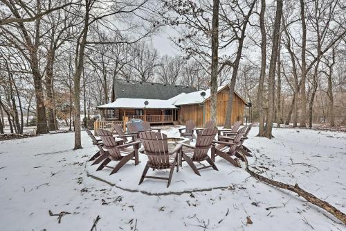 a group of chairs in the snow in front of a cabin at Country Cabin with Wraparound Deck and Views! in Springdale