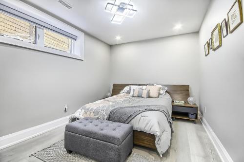 a white bedroom with a bed and a ottoman at Charming and Luxurious 2BR+1Bath Guest Suite in Toronto
