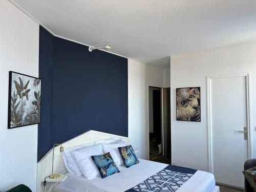 een slaapkamer met een blauwe muur en een bed met kussens bij Gabrielle hôtel in Aiguines