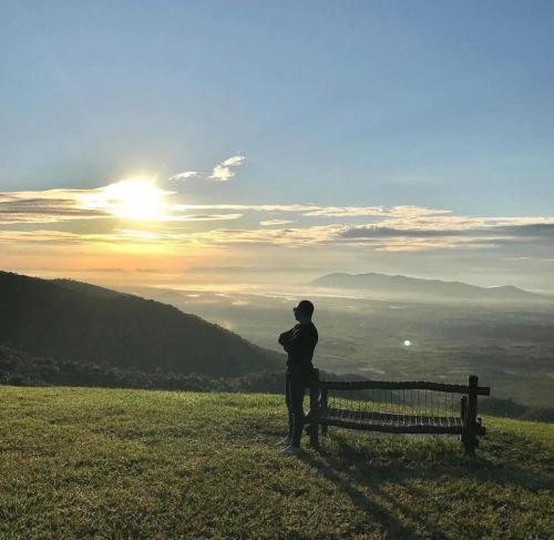 a man standing next to a bench on a hill at Sítio do Bosco Park in Tianguá