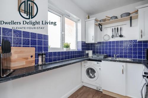 a kitchen with a washing machine and blue tiles at Dwellers Delight Living Ltd Serviced Accommodation Charming 3 Bedroom Flat, Chafford Hundred, Grays with Free Parking & Wifi in West Thurrock