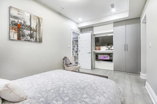 a white bedroom with a bed and a tv at Charming and Luxurious 2BR+1Bath Guest Suite in Toronto