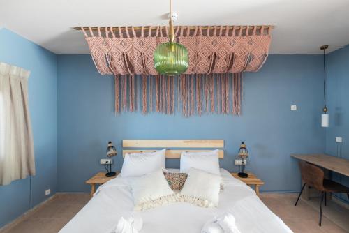 1 dormitorio con paredes azules y 1 cama con almohadas blancas en Selina Mantur Almog Dead Sea en Almog