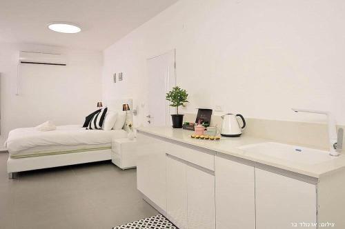 a white kitchen with a bed and a sink in a room at וילה אל סלבדור - וילה מדהימה עם בריכה פרטית וג'קוזי in Peqi‘in H̱adasha