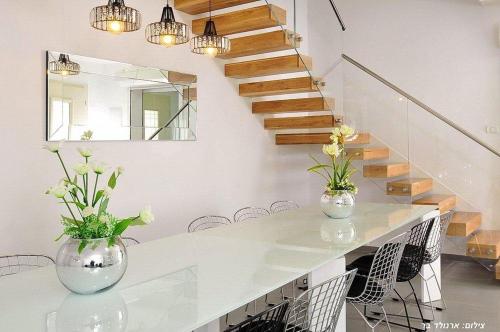 a dining room with a white table and stairs at וילה אל סלבדור - וילה מדהימה עם בריכה פרטית וג'קוזי in Peqi‘in H̱adasha