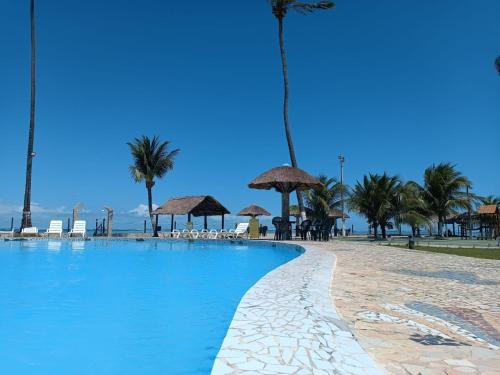 a swimming pool on the beach with palm trees at Village Galés de Maragogi in Maragogi