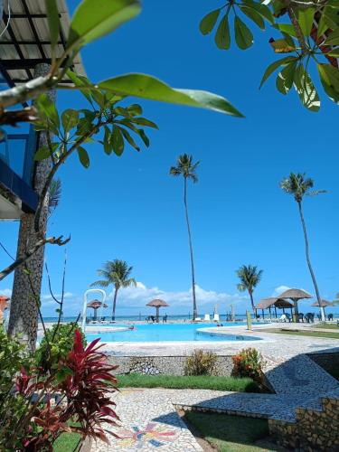 a beach with palm trees and a swimming pool at Village Galés de Maragogi in Maragogi