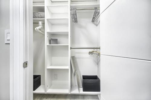 a closet with white shelves and a refrigerator at Charming and Luxurious 2BR+1Bath Guest Suite in Toronto