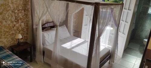 a bedroom with a canopy bed with white sheets at Pousada Canavieiras Frederic in Canavieiras