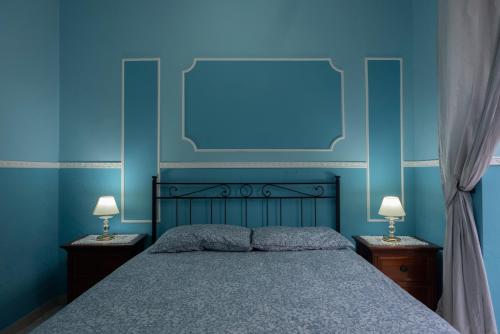 um quarto azul com uma cama e 2 candeeiros em SpaccaNapoli Home em Nápoles