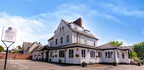 a white building with a sign in front of it at Woodcote Hotel in Hooton