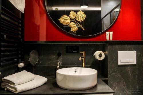La salle de bains est pourvue d'un lavabo blanc et d'un miroir. dans l'établissement D Apartments Centrum Ogień, à Białystok