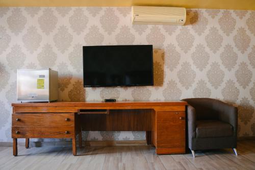 une télévision sur le dessus d'un bureau en bois avec une chaise dans l'établissement Hotel Casa Santa Lucia, à Zacatecas