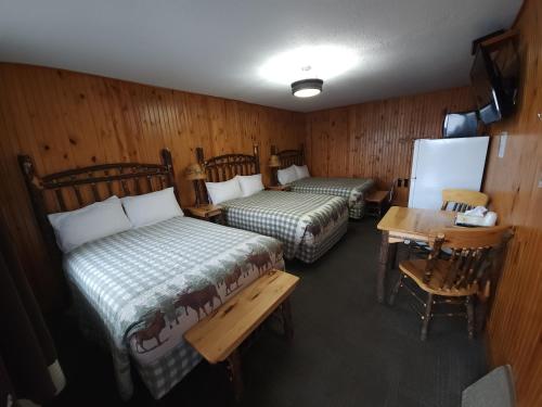 Cette chambre comprend deux lits, une table et un bureau. dans l'établissement Outdoorsman Motel, à Wawa