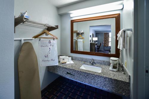 Americas Best Value Inn Douglasville في دوغلاسفيل: حمام مع حوض ومرآة