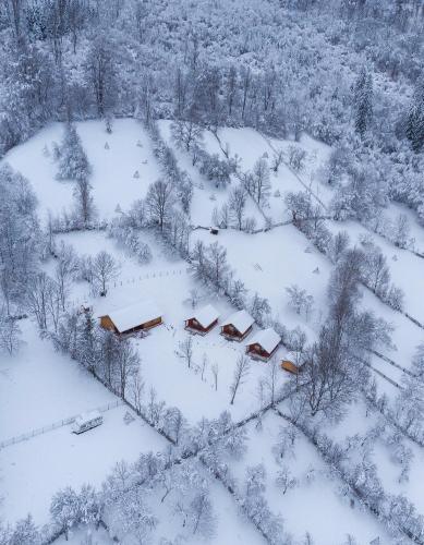 an aerial view of a snow covered field with houses at Complex turistic Traisteni din Valea Doftanei in Podu lui Neag