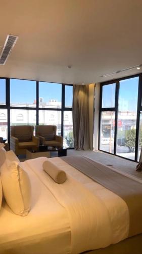 a large white bed in a room with large windows at White House Apartments in Khamis Mushayt