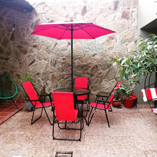 stół z czerwonymi krzesłami i parasol na patio w obiekcie El Molino Hostal w mieście El Carmen