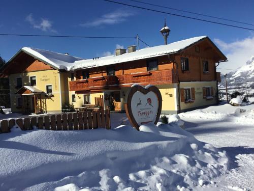 ein Gebäude mit einem Schild im Schnee in der Unterkunft Apparthaus Taxegger in Haus im Ennstal