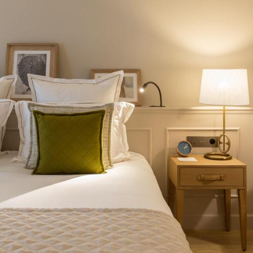 a bed with a green pillow and a lamp on a table at Hôtel Chais Monnet & Spa in Cognac
