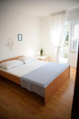 a white bedroom with a large bed and a window at Villa Claudia Lemon Appartment in Premantura