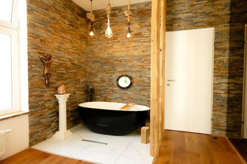 a bath tub in a room with a brick wall at XuBa ApartmentRooms I Wien Messe Prater I Küchenzeile in Vienna