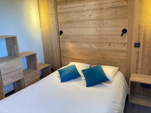 a bedroom with a white bed with two blue pillows at Bel appartement rénové - 8 pers, balcon, animaux admis - FR-1-634-86 in Morzine