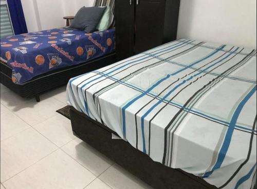 uma cama com lençóis azuis e brancos num quarto em Apartamento Cidade Ocian - Praia Grande - Edifício Van Gogh - Alto padrão 94mts - 2 Suítes na Praia Grande