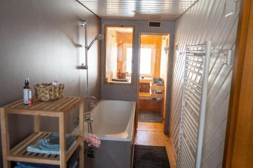 a bathroom with a bath tub and a sink at Ferienhaus "Hörli" im Toggenburg in Sankt Peterzell