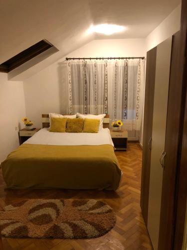 1 dormitorio con 1 cama grande con almohadas amarillas en Casa la Raisa en Lupeni
