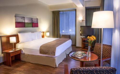 a hotel room with a large bed and a table at Del Prado Hotel in Lima