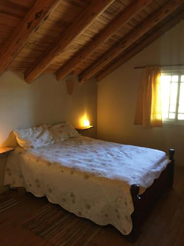 una camera da letto con un grande letto con lenzuola bianche e una finestra di Villa Pehuenia a Villa Pehuenia