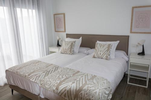 - une chambre dotée d'un grand lit avec des draps et des oreillers blancs dans l'établissement Apartamentos El Mirador de la Janda, à Benalup-Casas Viejas
