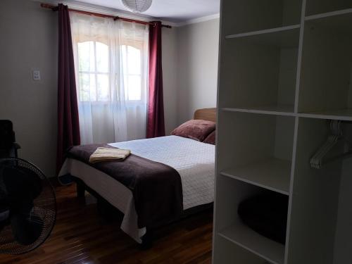 Habitación pequeña con cama y ventana en Un lugar encantador con una pequeña terraza en Iquique