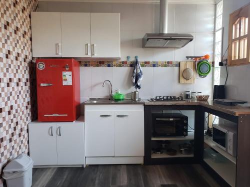 uma cozinha com armários brancos e um frigorífico vermelho em Un lugar encantador con una pequeña terraza em Iquique