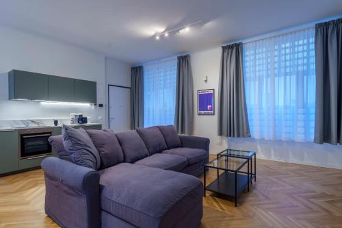 uma sala de estar com um sofá roxo e uma cozinha em [DUOMO-PORTA VENEZIA]LUXURY WIFI E NETFLIX em Milão