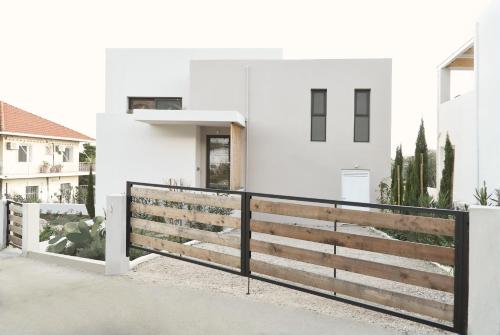 a white house with a wooden fence at Villa Mouria private villa just 200m from the sea in Pogoniá