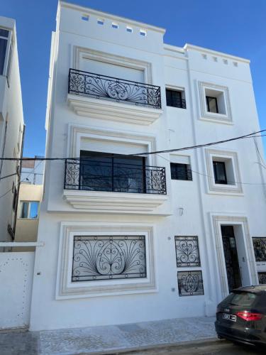 a white building with two balconies and a car parked in front at Marsa Authentic Luxury Appart 1 in La Marsa