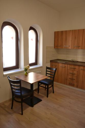 a kitchen with a table and chairs and two windows at Hostel Děčín Na Skřivánce in Děčín