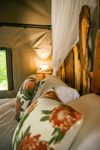a bed with a wooden head board with a flower pillow at HighlandsView in Swellendam
