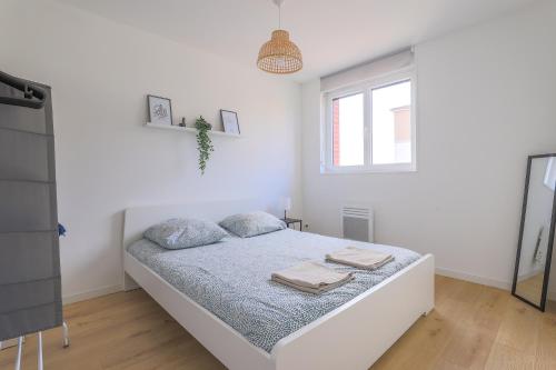a white bedroom with a bed with towels on it at Appartement Familial - Avec Parking Privé Gratuit in Arras