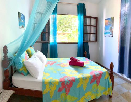 a bedroom with a bed and a window with blue curtains at <CASA COLIBRI> La Désirade in Les Galets
