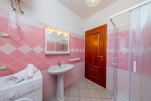 a pink bathroom with a sink and a shower at Appartamento sette posti vicino al centro di San Teodoro in San Teodoro