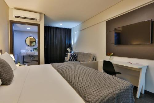 a hotel room with a large bed and a desk at Executive Inn Fernandopolis in Fernandópolis