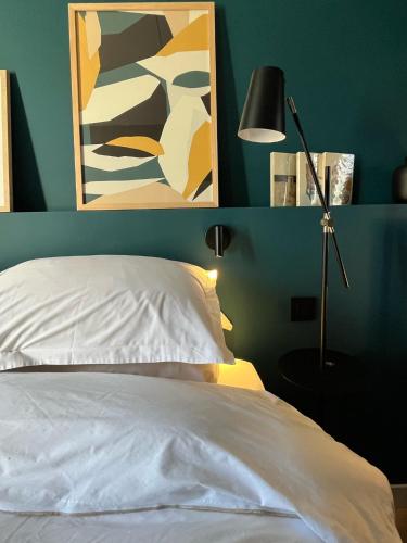 a bedroom with a bed and a lamp and a painting at Ostan Hôtel Boutique in Roquebillière