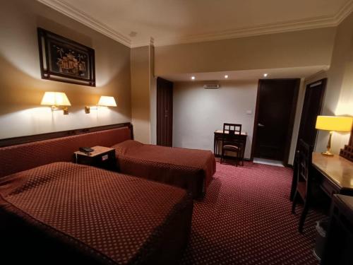 a hotel room with two beds and a table at Queen Hotel Fayoum in Fayoum