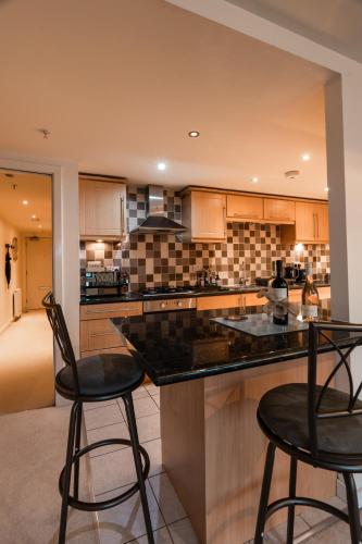 a kitchen with two bar stools and a counter at West End Escape - Prime Location in Glasgow