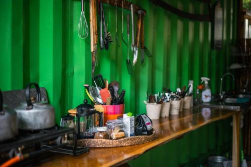 a green wall with a wooden counter with utensils at HighlandsView in Swellendam