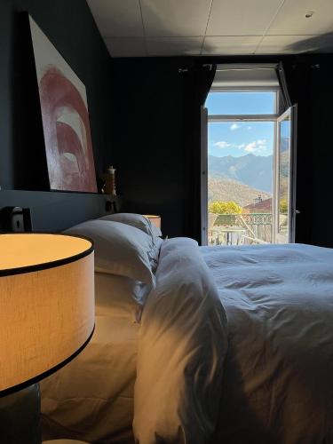 a bedroom with a bed and a table and a window at Ostan Hôtel Boutique in Roquebillière