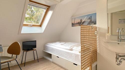 a small bedroom with a bed and a window at Frauenhotel Hanseatin - Women Only in Hamburg